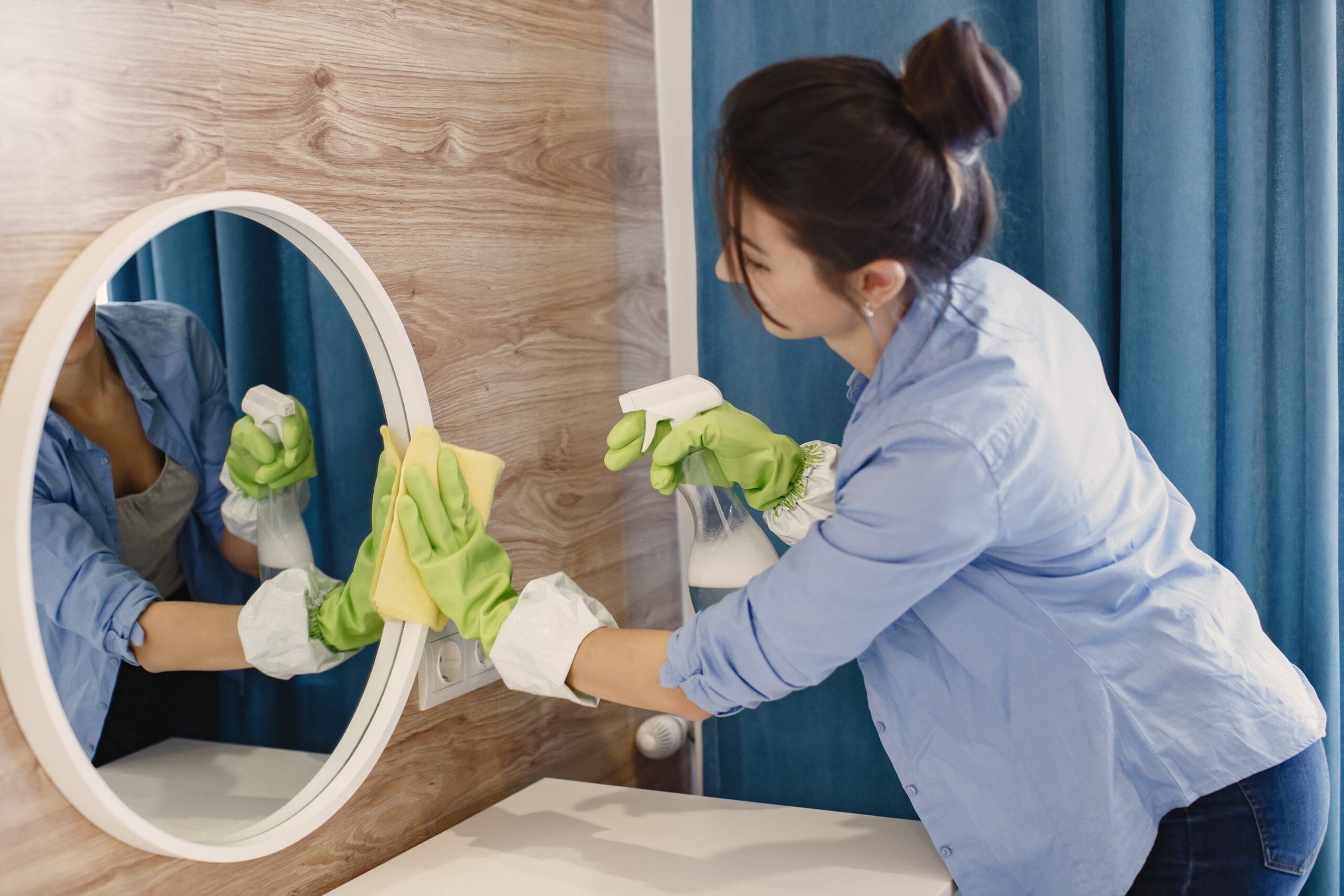 Woman cleaning a mirror with fresh scent cleaning spray