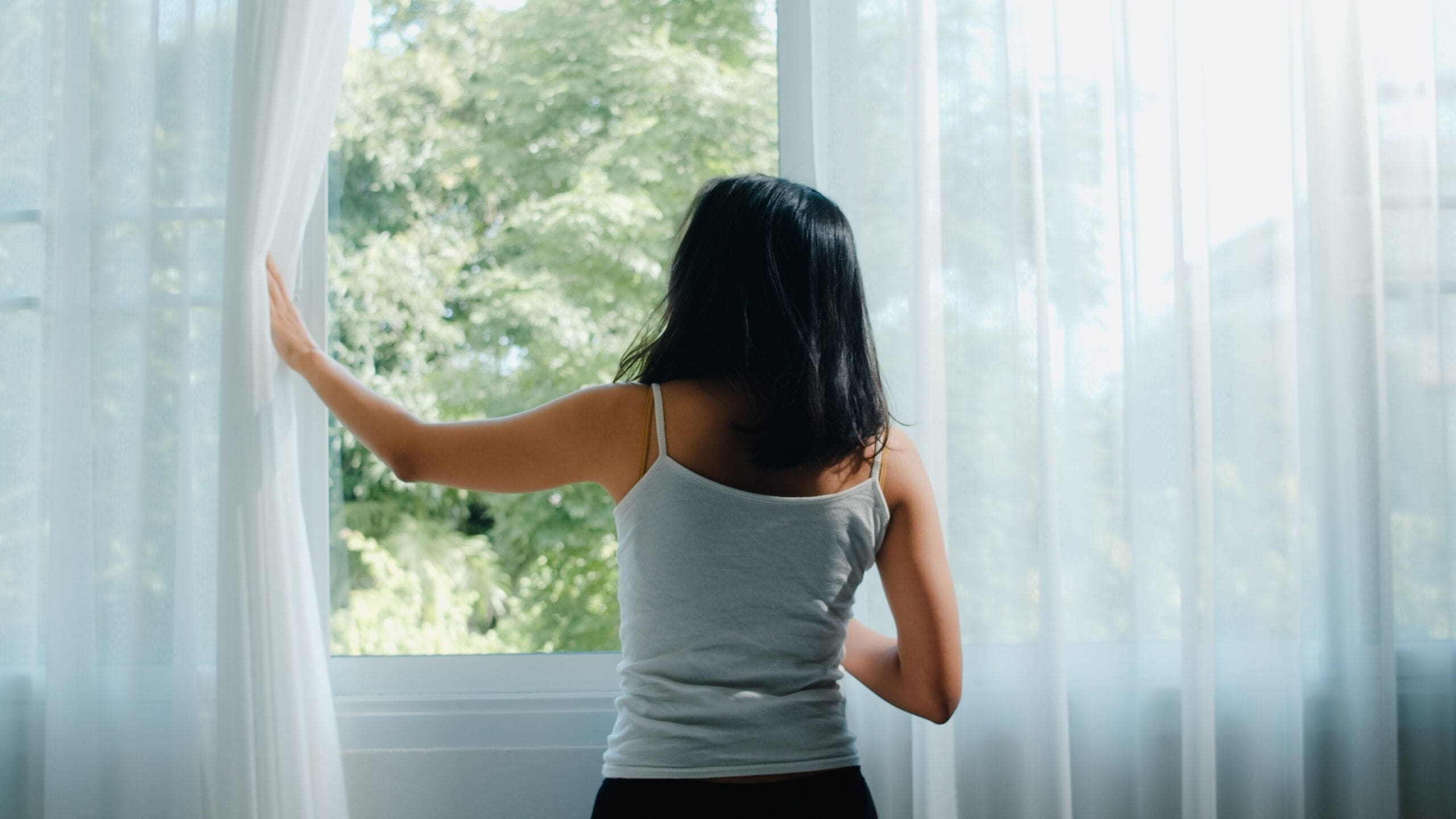 Woman opening up a window for fresh air scent