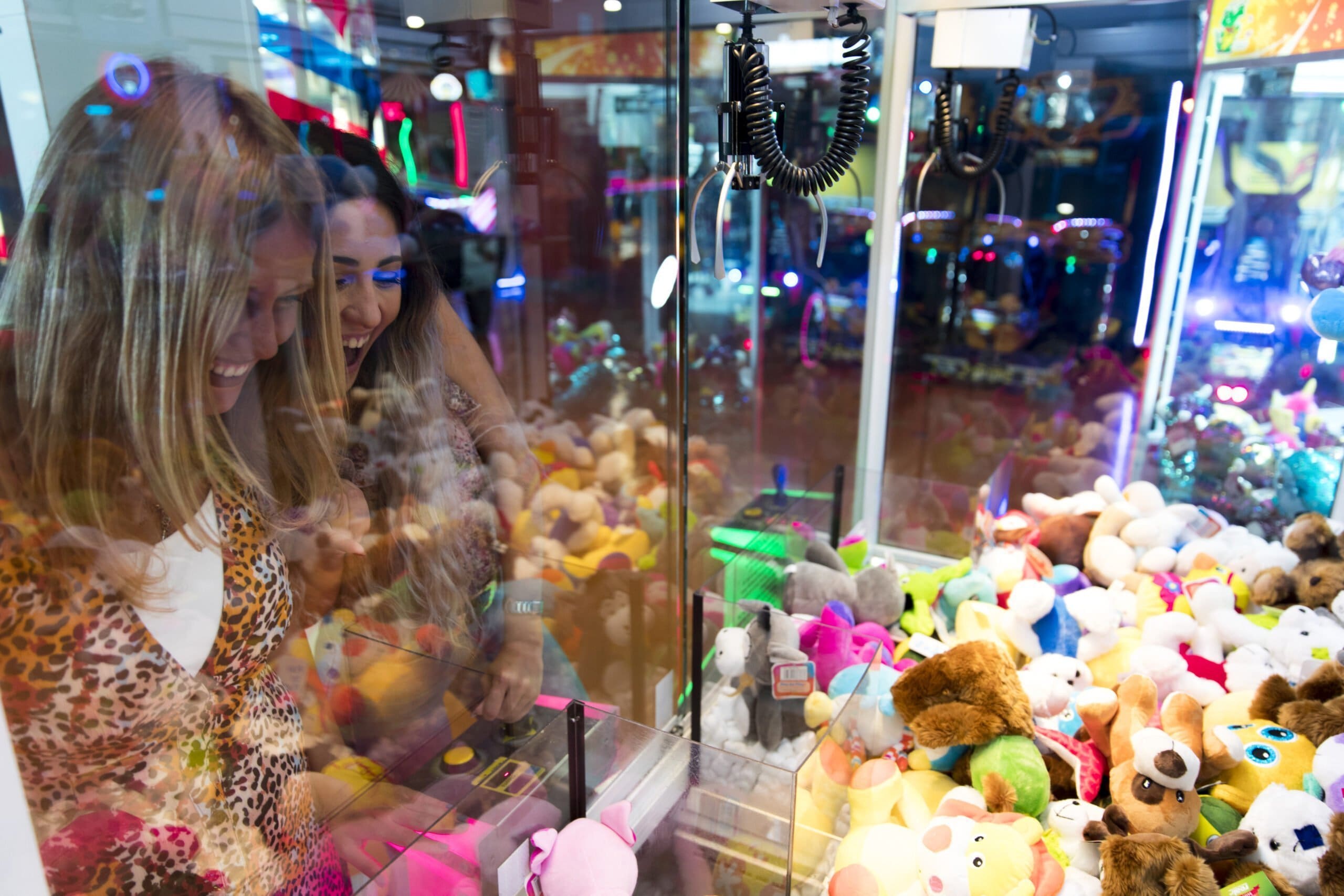 Two women playing an arcade claw game