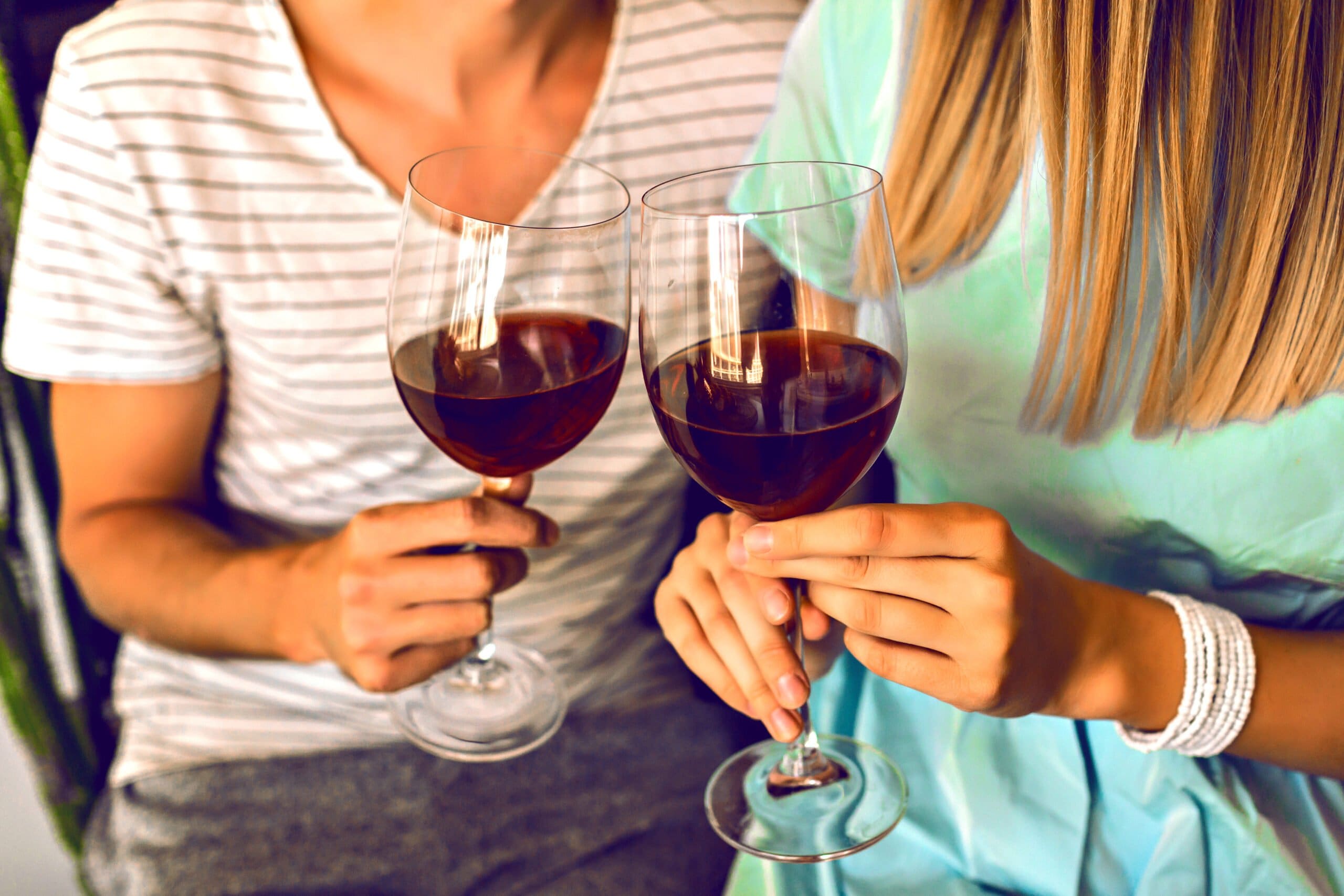 two people with wine glasses making the cheers gesture