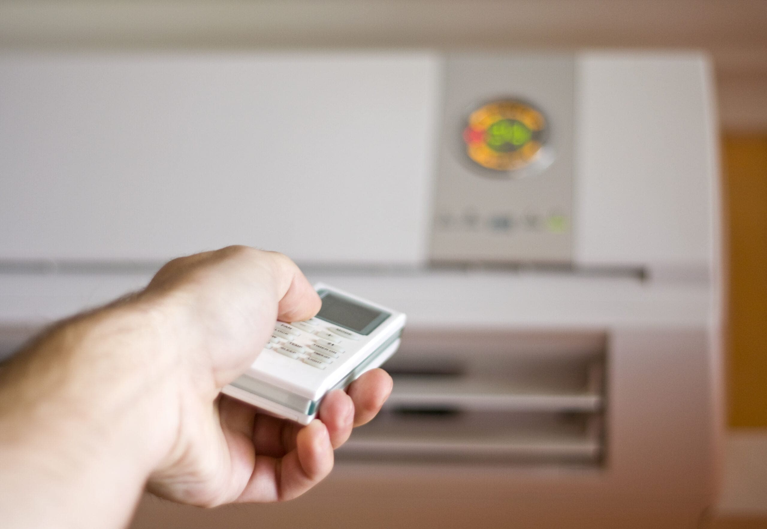 homeowner using remote to turn up the air conditioning unit in their home