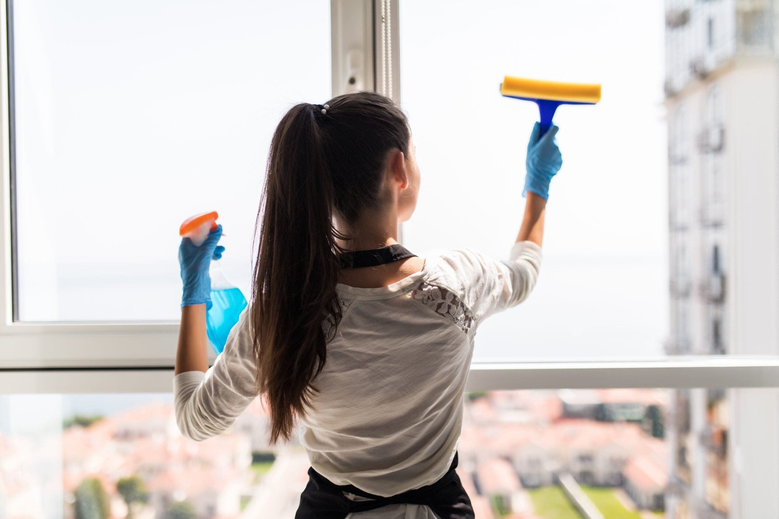 professional house cleaners cleaning windows to maximize the value of your home before selling it.