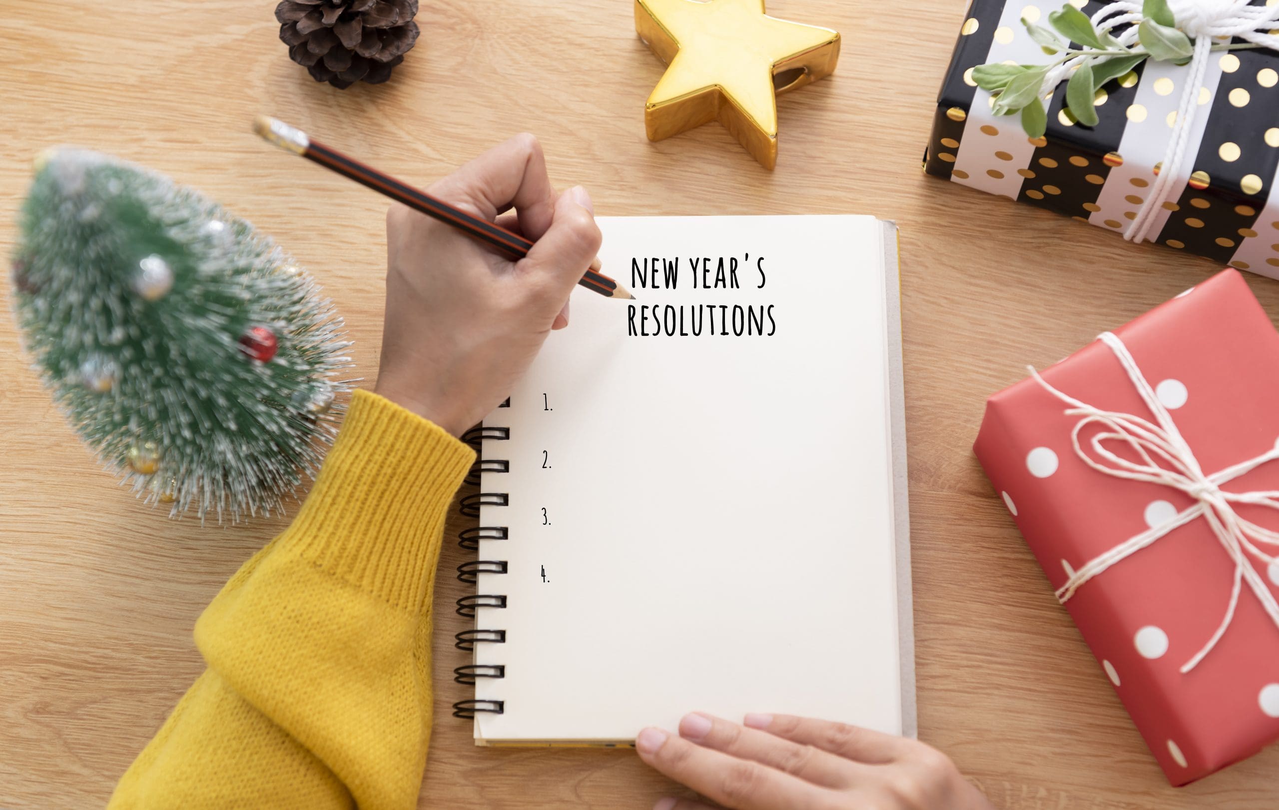 woman writing new years resolutions for homeowners on a notebook at a desk