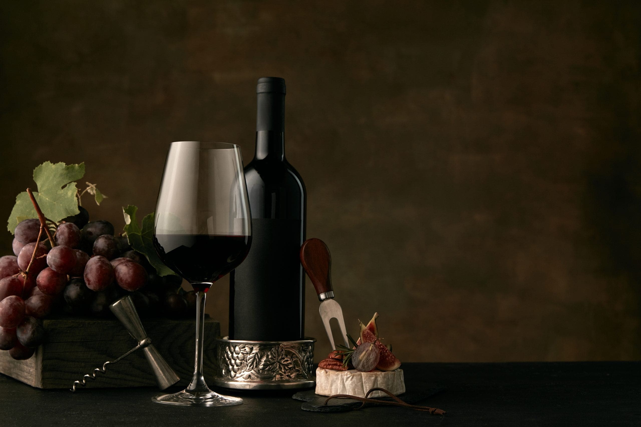 Wine bottle and glass with home wine essentials of bottle opener, wine stand, and accessories