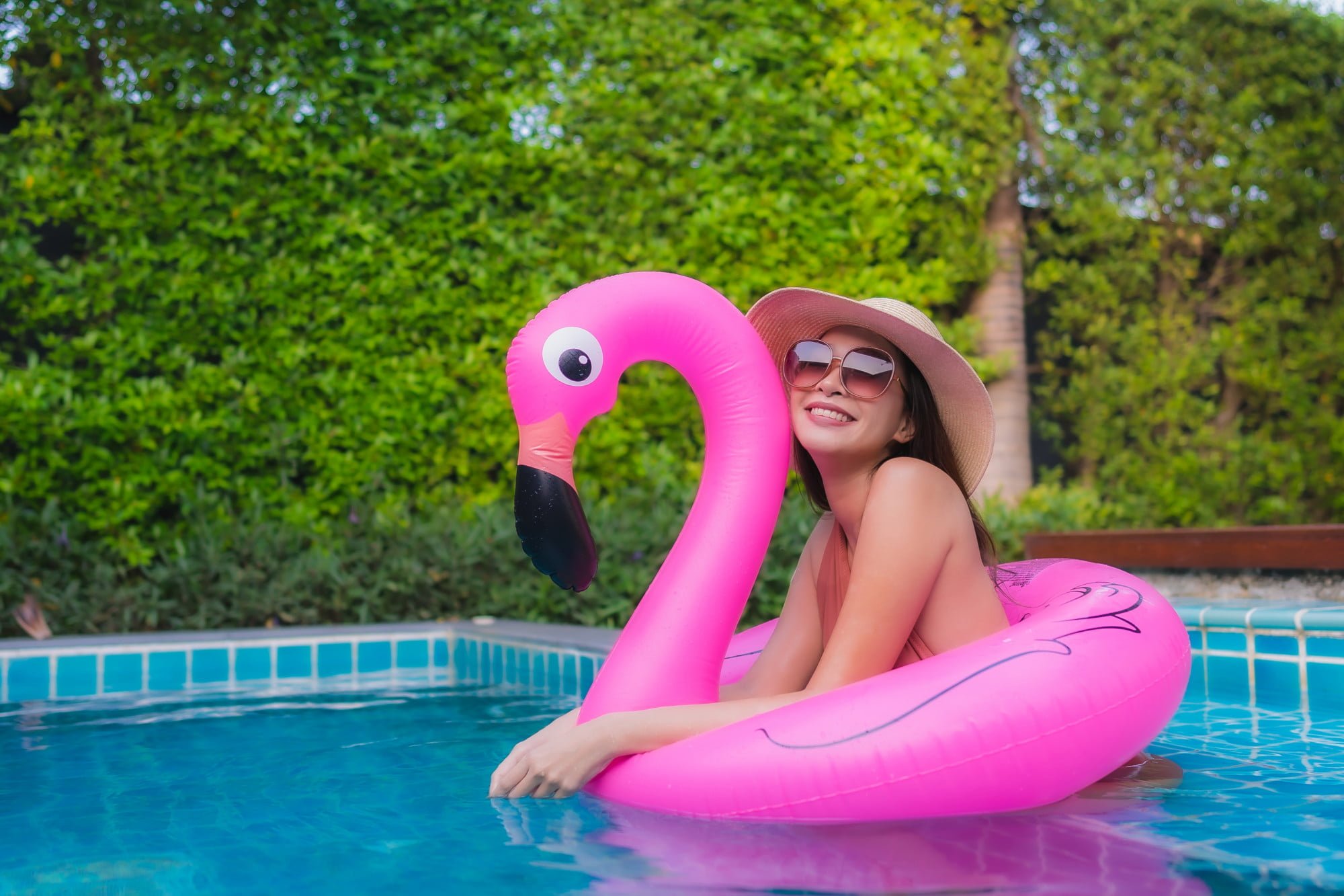 woman on inflatable pool float of a flamingo in home swimming pool