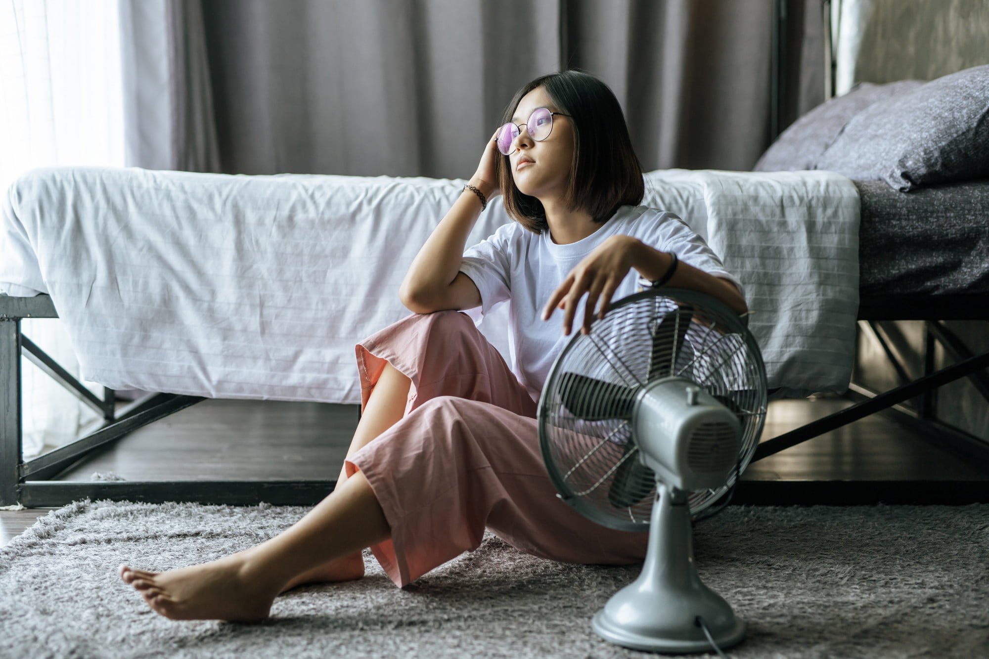 woman-in-front-of-fan-in-bedroom-looking-for-ways-to-cool-down-your-home-in-the-summer.