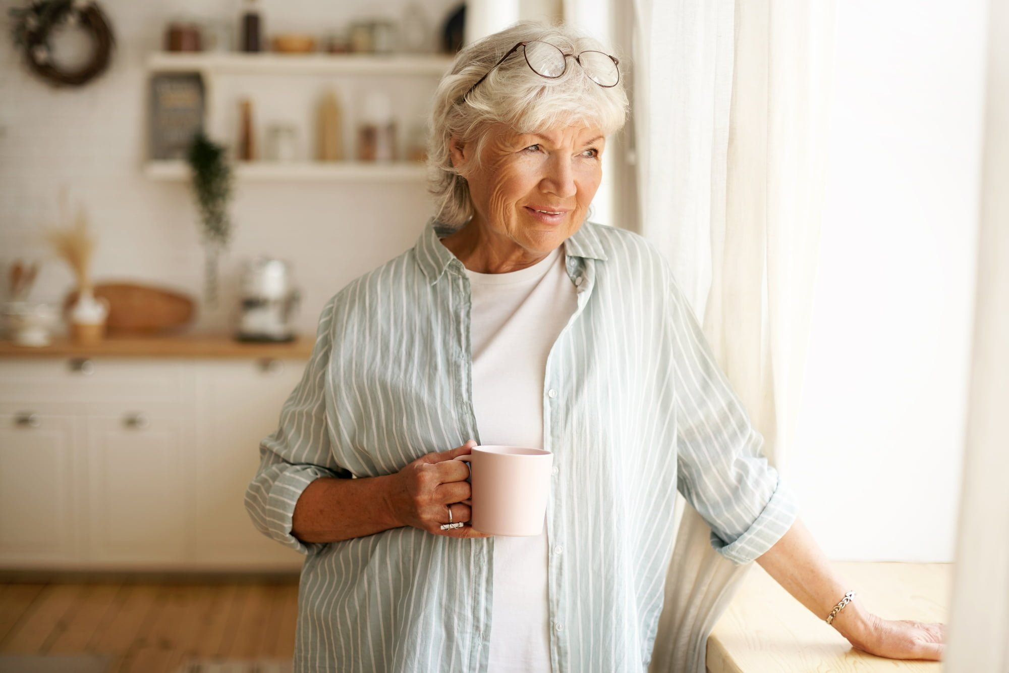 senior woman drinking coffee in new home after following downsizing and moving tips for seniors