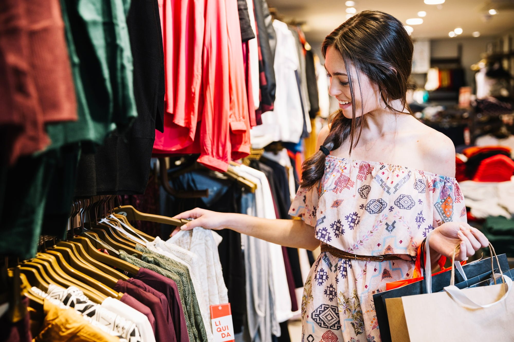 young woman supporting small businesses in saratoga county shopping for clothes through racks